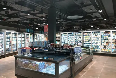 Elektrotechnik im Einzelhandel mit beleuchteten Kühlregalen, Deckeninstallationen und Versorgungstechnik im Frischebereich.