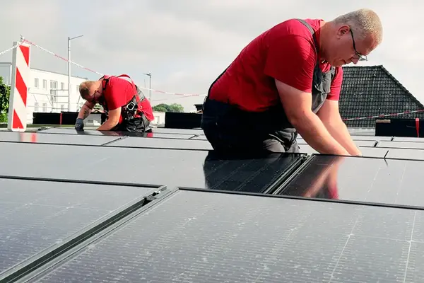 Zwei Monteure verkabeln eine gewerbliche PV-Anlage in Lübeck
